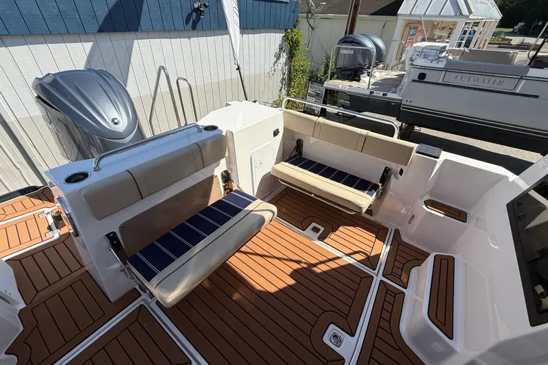 Slide: The Image of 2026 Ranger Tugs R-25 boat interior with cushioned seating and wood-patterned flooring. - 25