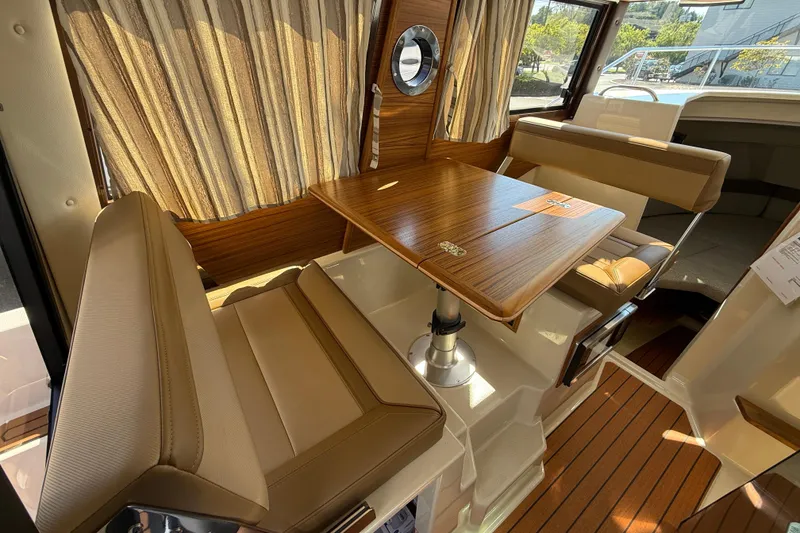 Slide: The Image of 2026 Ranger Tugs R-25 interior with elegant wood table and beige seating. - 7