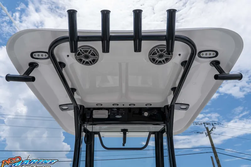 Slide: The Image of 2026 Sea Hunt Gamefish 25 T-top with rod holders and speakers against blue sky. - 18