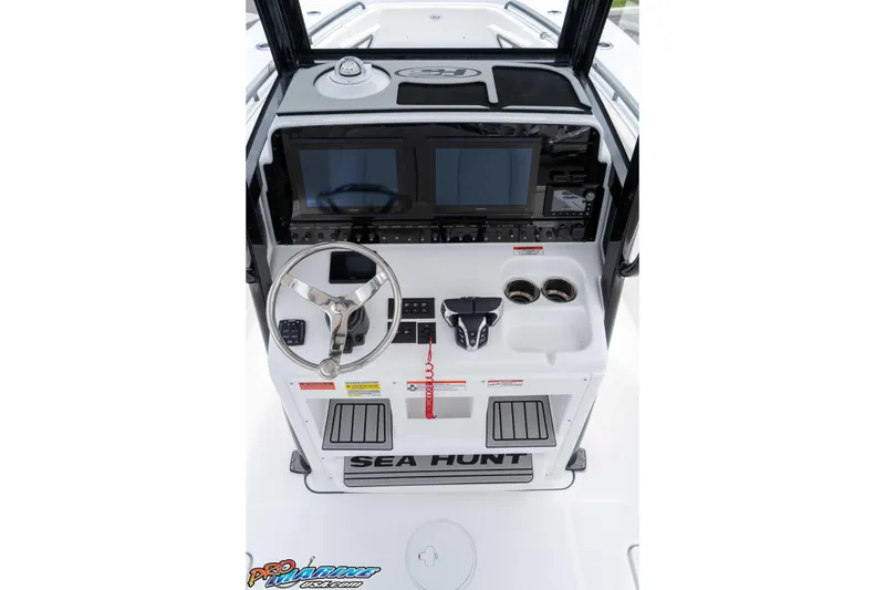 Slide: The Image of 2026 Sea Hunt Gamefish 25 helm with dual screens, steering wheel, and control panel. - 26