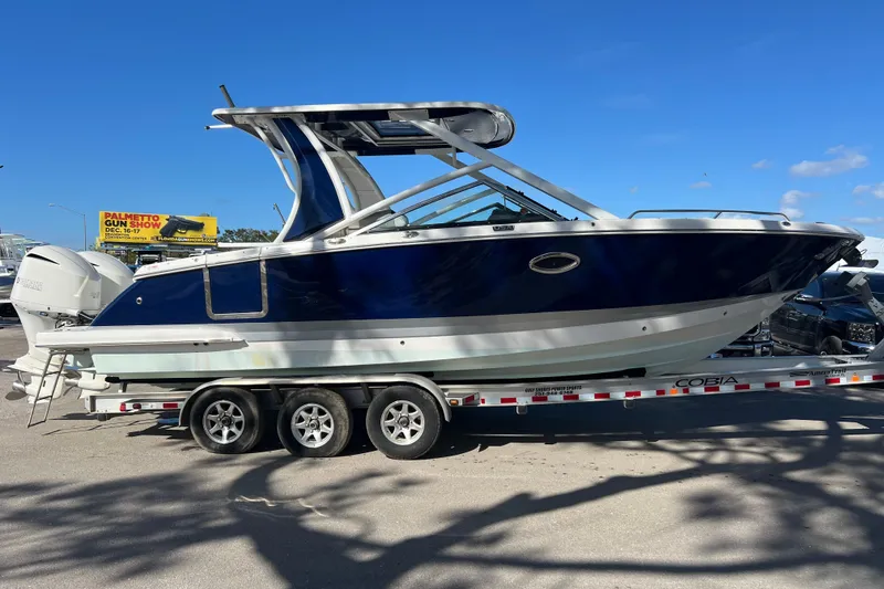 Slide: The Image of 2020 Chaparral 280 OSX boat on trailer, blue and white design, clear sky background. - 2