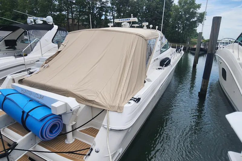 Slide: The Image of 1998 Sea Ray 630 Super Sun Sport yacht docked, covered with beige tarp, blue mat on deck. - 35