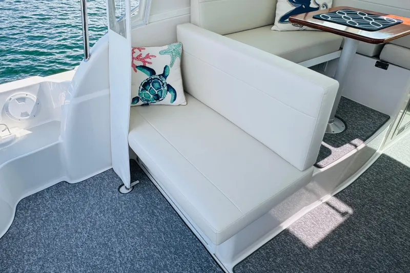 Slide: The Image of 2025 Back Cove 34O boat interior with white seating and decorative pillows. - 23