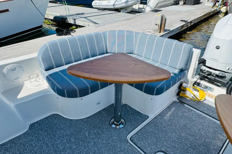 Slide: The Image of Cozy seating area on 2025 Back Cove 34O boat with striped cushions and triangular table. - 29