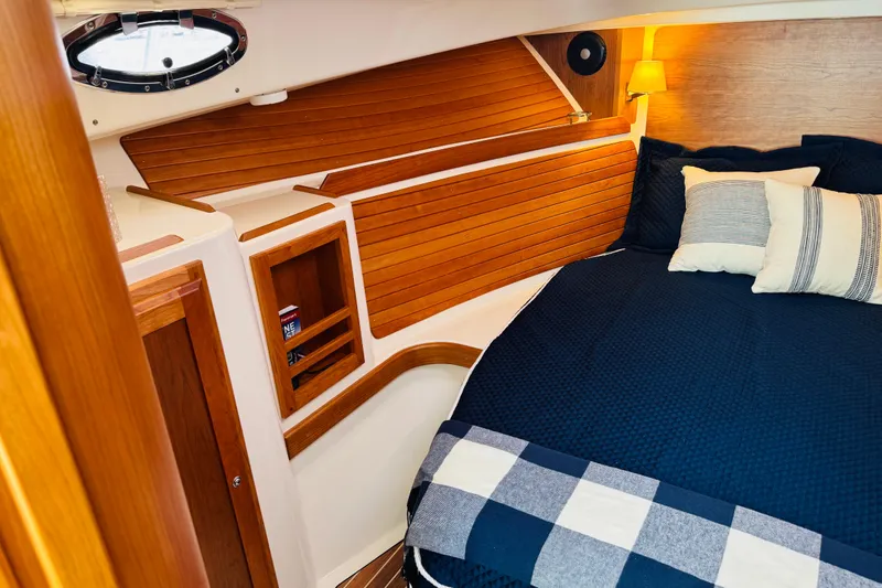 Slide: The Image of Cozy cabin interior of 2025 Back Cove 34O with wood paneling and navy bedding. - 3