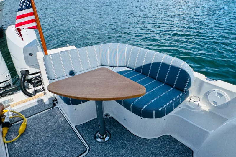 Slide: The Image of 2025 Back Cove 34O boat with striped seating and triangular table on deck. - 30