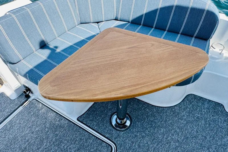 Slide: The Image of Back Cove 34O 2025 boat interior with triangular wooden table and striped seating. - 32
