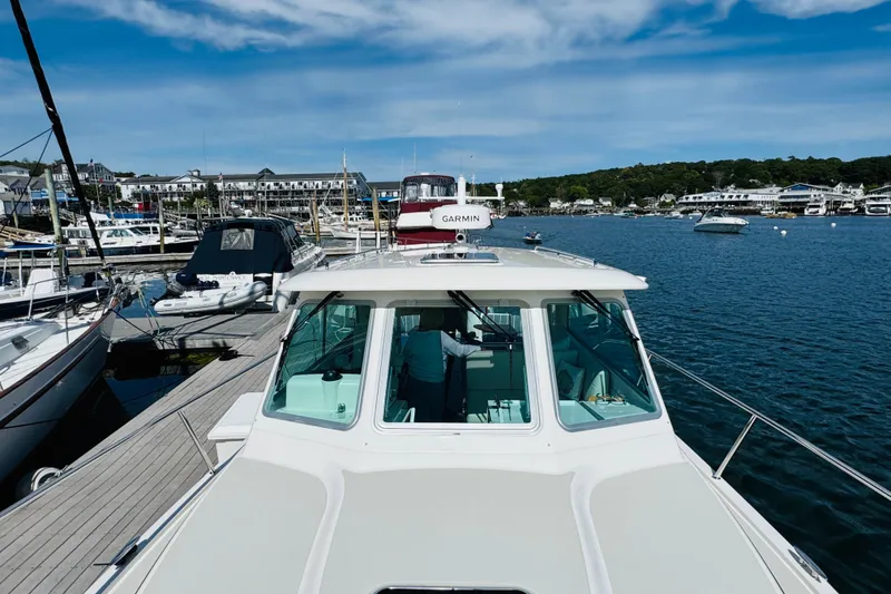 Slide: The Image of 2025 Back Cove 34O docked at a marina, surrounded by boats and scenic waterfront. - 33