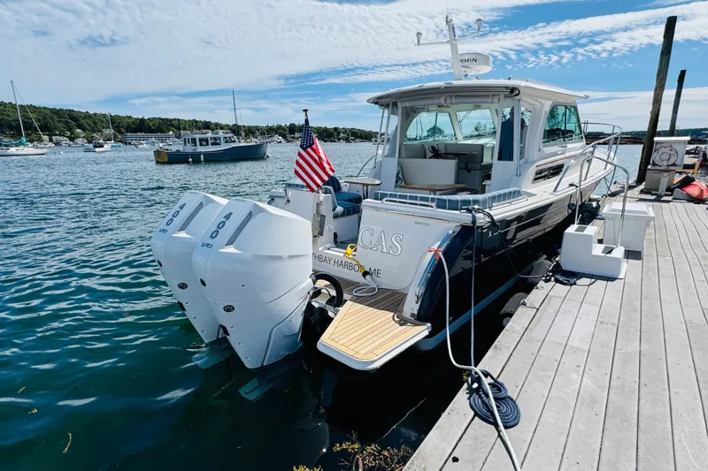 Slide: The Image of 2025 Back Cove 34O boat docked, featuring dual outboard engines and American flag. - 43