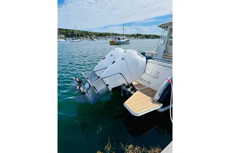 Slide: The Image of 2025 Back Cove 34O boat with dual outboard engines docked in a scenic harbor. - 44