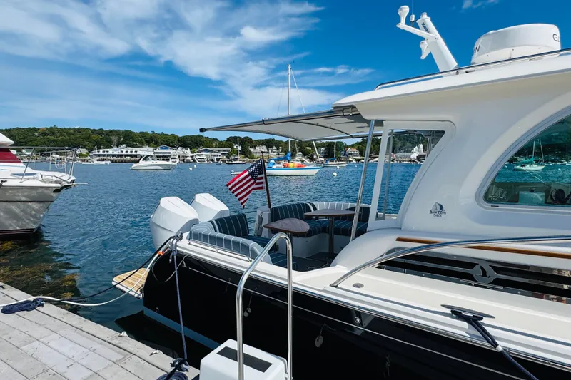 Slide: The Image of 2025 Back Cove 34O yacht docked at marina, featuring sleek design and American flag. - 45