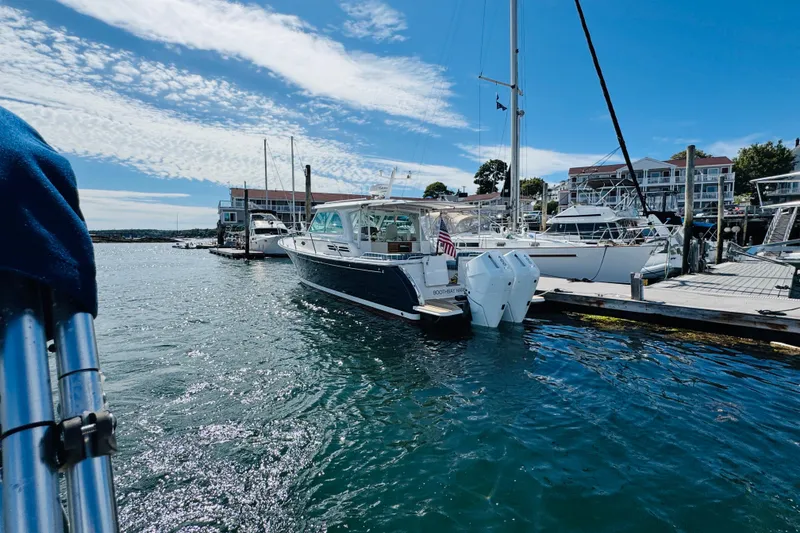 Slide: The Image of 2025 Back Cove 34O boat docked in a sunny marina with clear blue skies. - 47