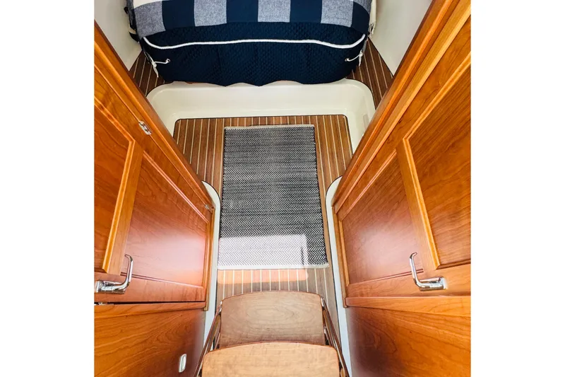Slide: The Image of 2025 Back Cove 34O cabin interior with wooden finish and striped bedding. - 9
