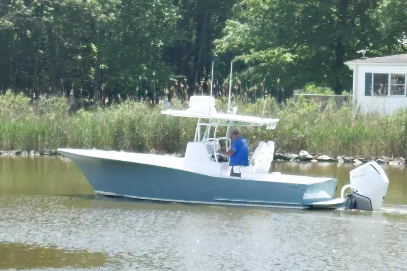 The Image of 2025 Weaver 270 boat cruising on a calm river near a wooded shoreline. - 1