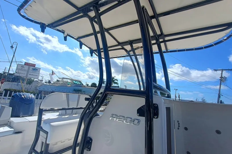 Slide: The Image of 2026 Robalo R200 Center Console boat with T-top under a clear blue sky. - 16