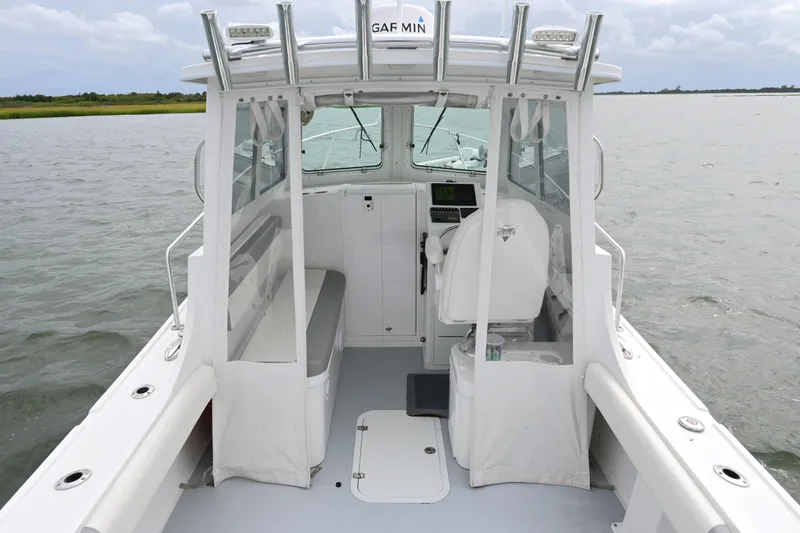 Slide: The Image of 2022 Steiger Craft 255DV Miami boat interior with helm and seating on calm water. - 21