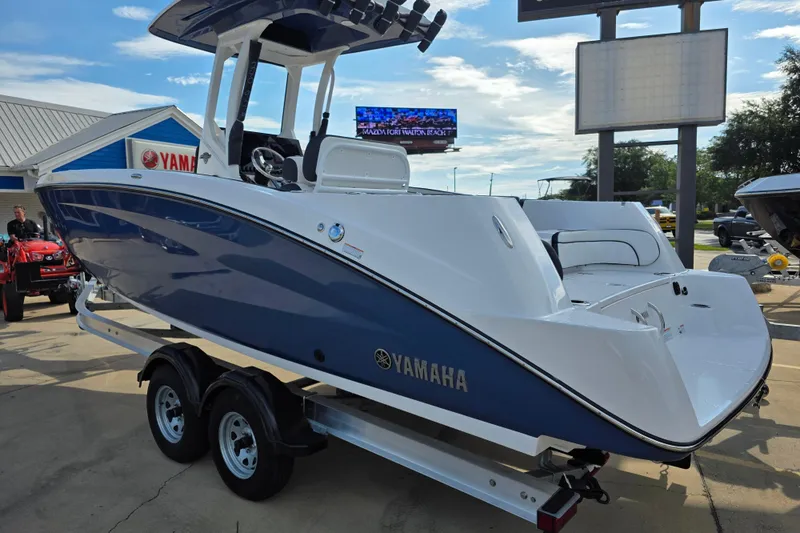 Slide: The Image of 2025 Yamaha Boats 252 FSH Sport in blue and white on a trailer at a dealership. - 3