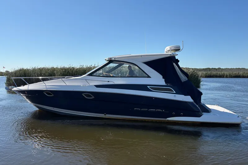 Slide: The Image of 2013 Regal 35 Sport Coupe boat on calm water under clear blue sky. - 5