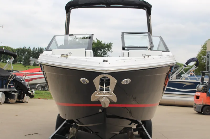 The Image of 2025 Cobalt R6 boat on trailer, black hull with red stripe, parked outdoors. - 1