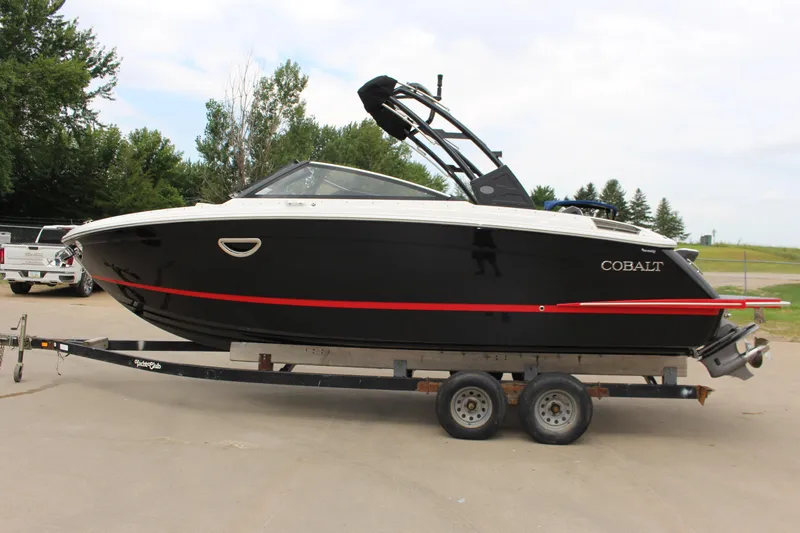 Slide: The Image of 2025 Cobalt R6 boat on trailer, black with red stripe, parked outdoors. - 38
