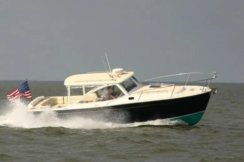 The Image of 2009 MJM 29z Express boat cruising with American flag on open water. - 0