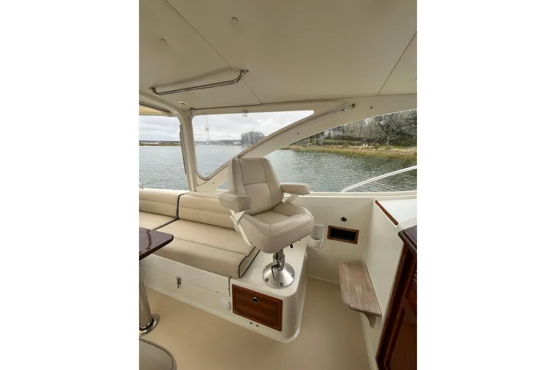 Slide: The Image of 2009 MJM 29z Express boat interior with beige seating and helm chair by the water. - 13