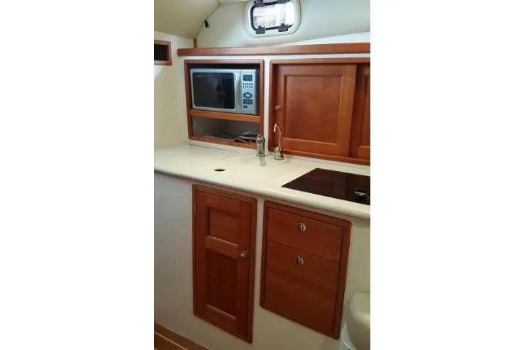 Slide: The Image of 2009 MJM 29z Express yacht interior with wooden cabinets, microwave, and sink. - 20