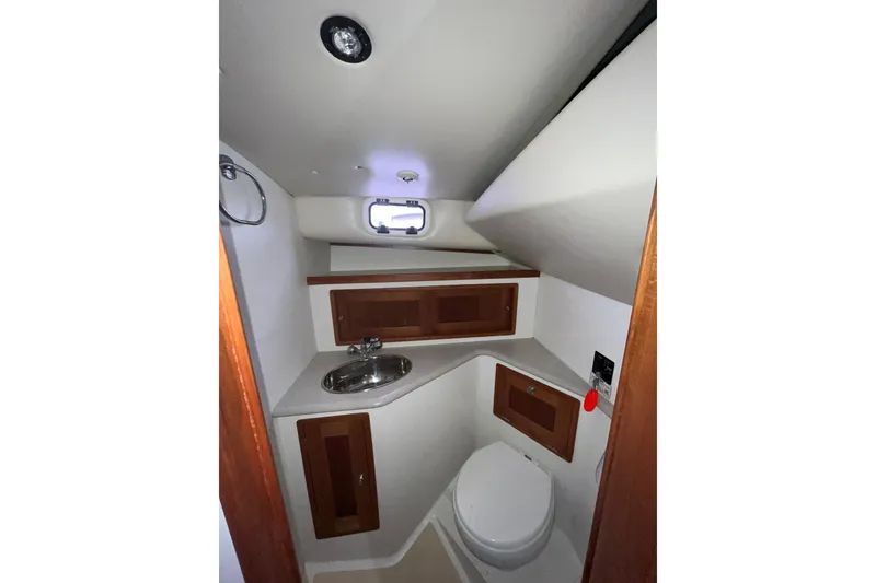 Slide: The Image of 2009 MJM 29z Express boat bathroom with sink, toilet, and wooden cabinets. - 24