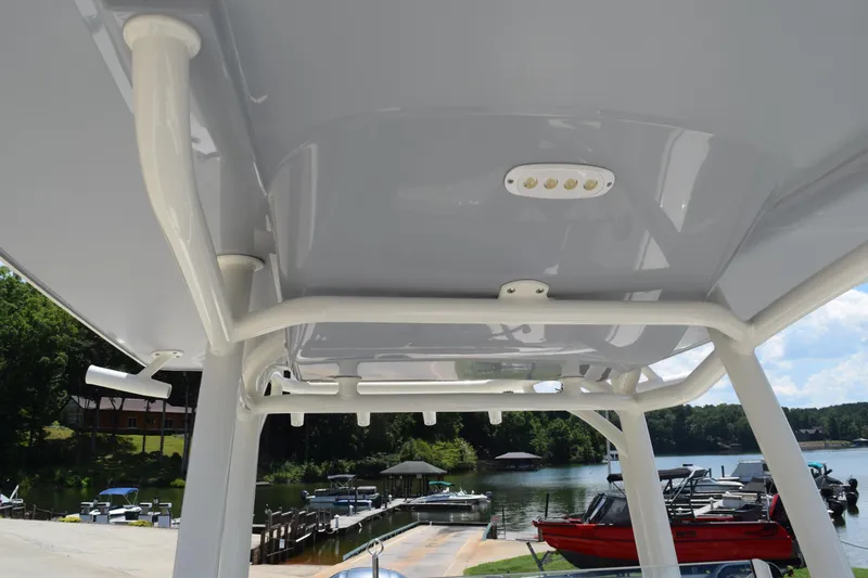 Slide: The Image of 2021 Stingray 236CC boat's T-top with integrated lighting, docked by a scenic lake. - 41
