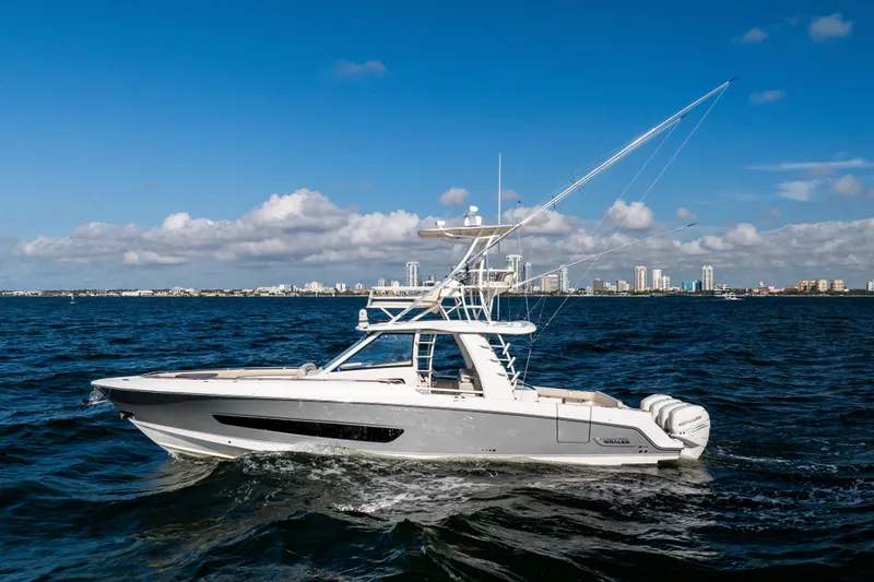 The Image of 2021 Boston Whaler 420 Outrage cruising on open water with city skyline backdrop. - 0