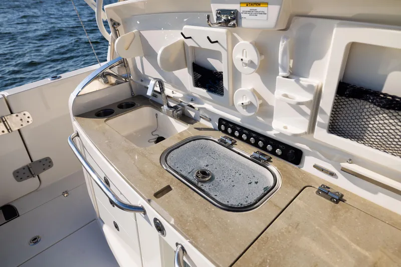 Slide: The Image of Boston Whaler 420 Outrage 2021 boat galley with sink and storage, on open water. - 35