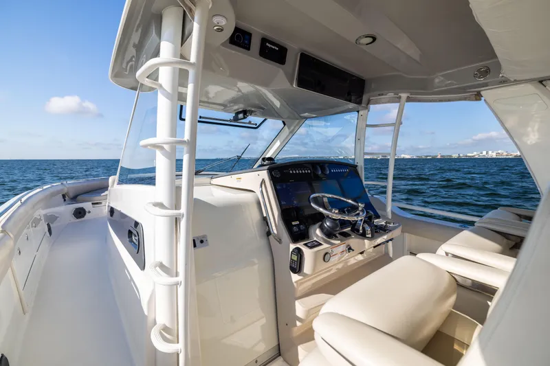 Slide: The Image of 2021 Boston Whaler 420 Outrage helm with ocean view, featuring modern controls and seating. - 48
