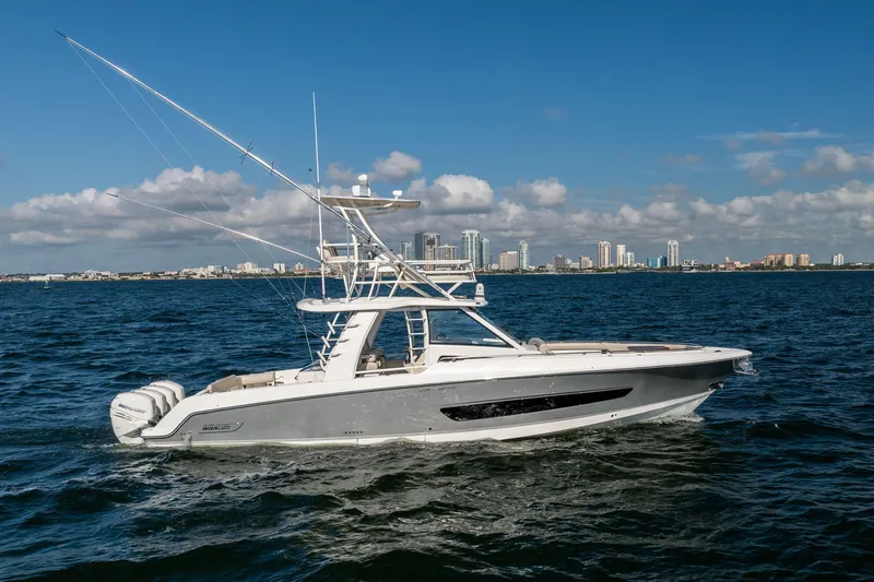 Slide: The Image of 2021 Boston Whaler 420 Outrage boat cruising on open water with city skyline backdrop. - 8