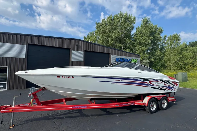 Slide: The Image of 2004 Baja 275 boat on red trailer, parked outside a marine facility. - 1