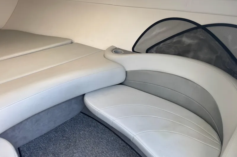 Slide: The Image of Interior seating of a 2004 Baja 275 boat, featuring beige upholstery and a cup holder. - 14