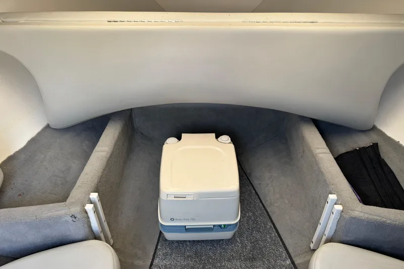 Slide: The Image of 2004 Baja 275 boat interior with portable toilet and carpeted flooring. - 19