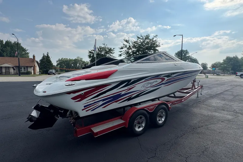 Slide: The Image of 2004 Baja 275 speedboat on trailer, featuring dynamic graphics, parked in suburban area. - 5