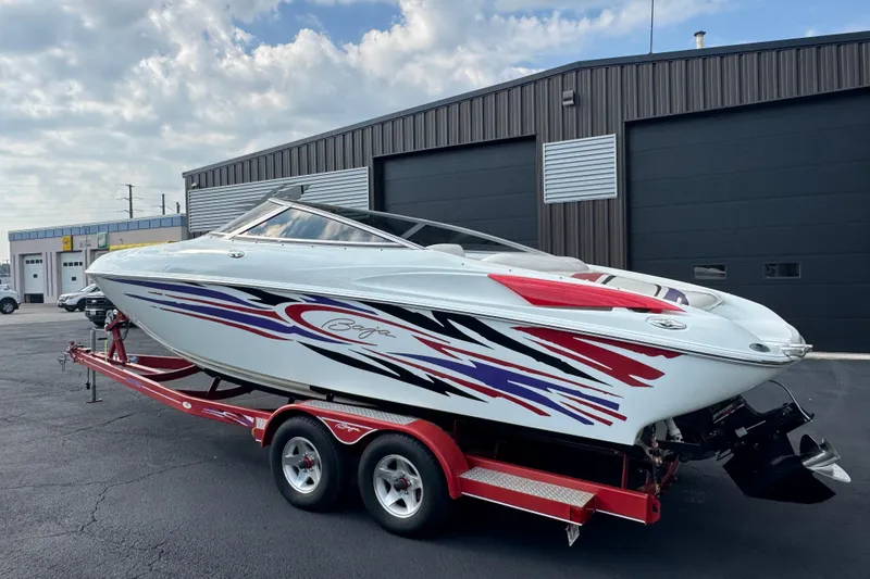 Slide: The Image of 2004 Baja 275 speedboat with vibrant graphics on a red trailer, parked outside a garage. - 7