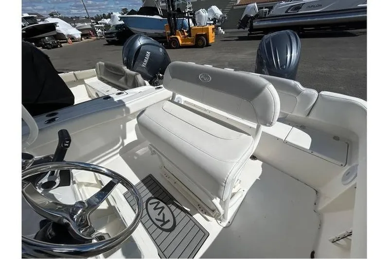Slide: The Image of 2024 Key West 203 FS boat interior with steering wheel and seating in a marina setting. - 6