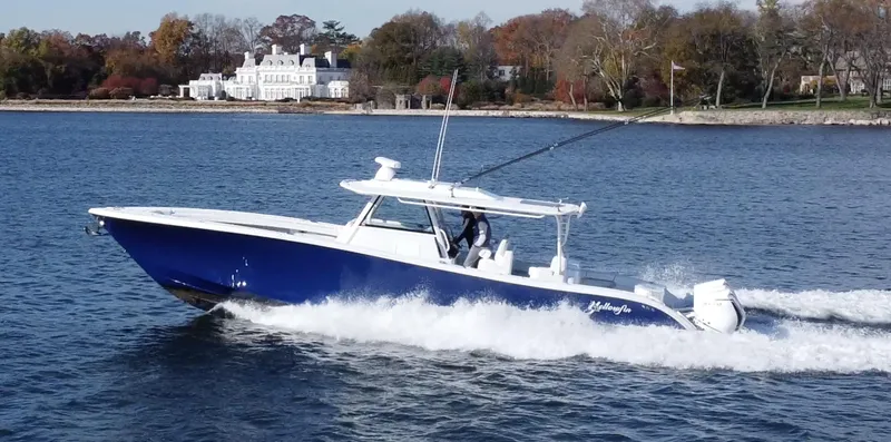 Slide: The Image of 2023 Yellowfin 42 Offshore boat cruising on a scenic lake with a mansion in the background. - 2