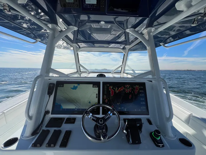 Slide: The Image of 2023 Yellowfin 42 Offshore boat dashboard with navigation screens, steering wheel, and ocean view. - 7