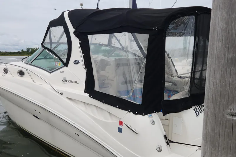 Slide: The Image of 2005 Sea Ray 320 Sundancer boat with black canopy docked in calm waters. - 0