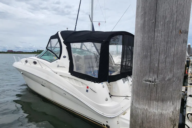 Slide: The Image of 2005 Sea Ray 320 Sundancer docked, featuring a black canopy and sleek white design. - 1