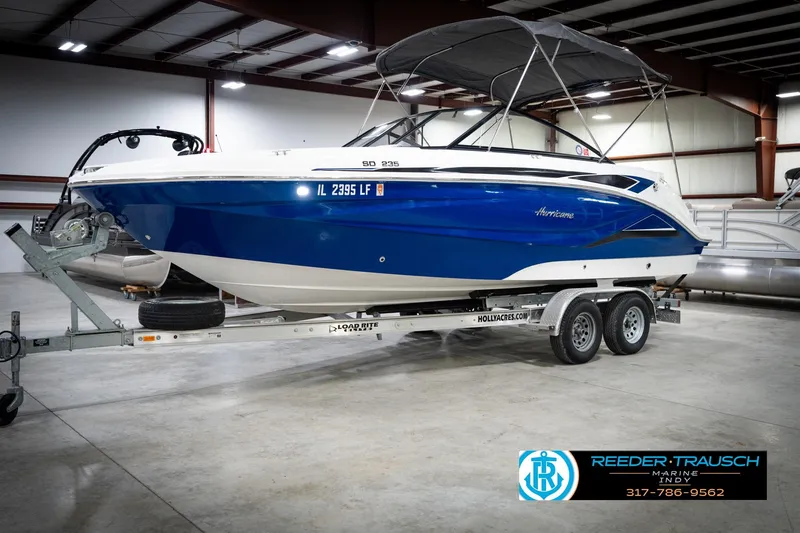 Slide: The Image of 2022 Hurricane 235RD boat on trailer in indoor showroom, blue and white design. - 3