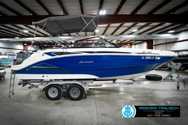 Slide: The Image of 2022 Hurricane 235RD boat in showroom, blue and white design, on trailer. - 6