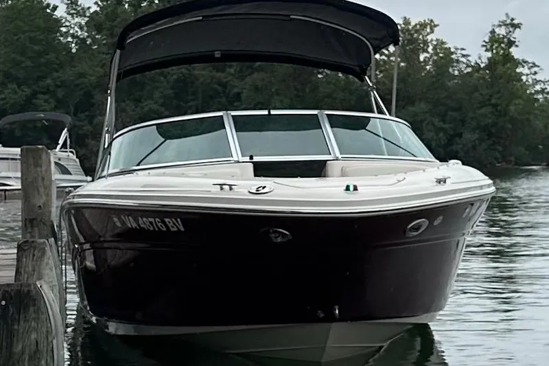 Slide: The Image of 2006 Sea Ray 220 Select boat docked on a calm lake with trees in the background. - 13