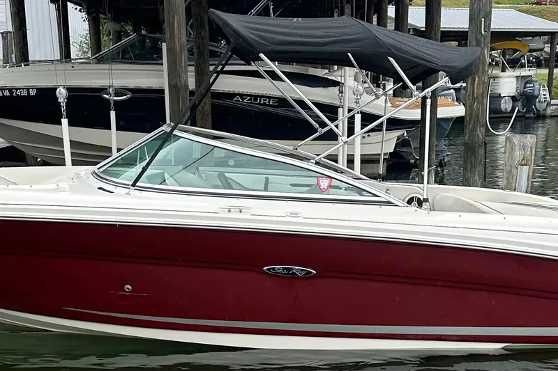 Slide: The Image of 2006 Sea Ray 220 Select boat with red hull and black canopy docked at marina. - 2