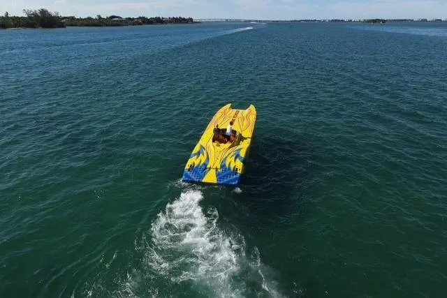 Slide: The Image of Aerial view of a 2007 MTI 40RP speedboat with vibrant yellow and blue design on open water. - 3
