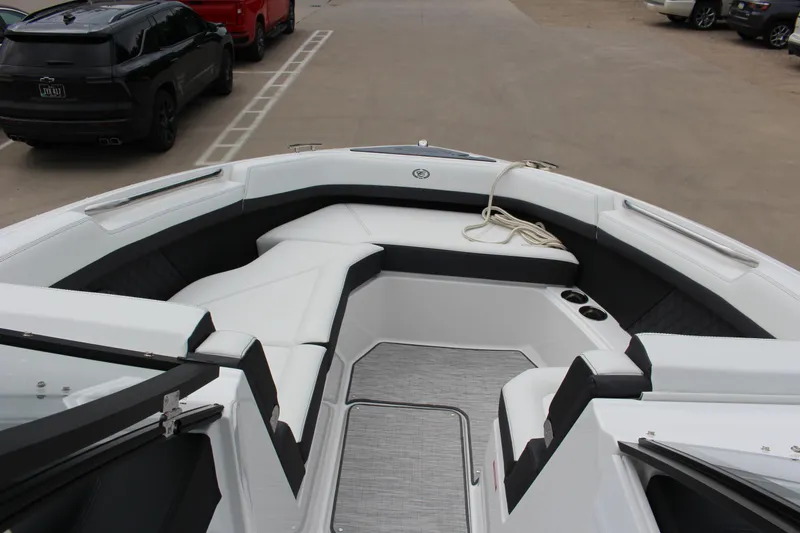 Slide: The Image of 2025 Cobalt R8 boat interior with white seating and cup holders, parked near vehicles. - 12