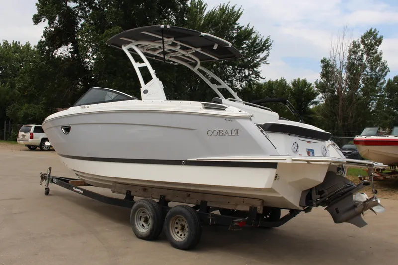 Slide: The Image of 2025 Cobalt R8 boat on trailer, parked outdoors with trees in the background. - 43